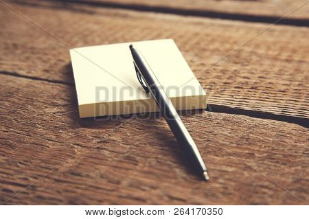 Pen On Yellow Page On Wooden Desk