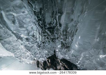 Winter Baikal. Olkhon Island. Ice Grotto. Thick Blue Ice And Icicles On The Coastal Rocks Of Olkhon 