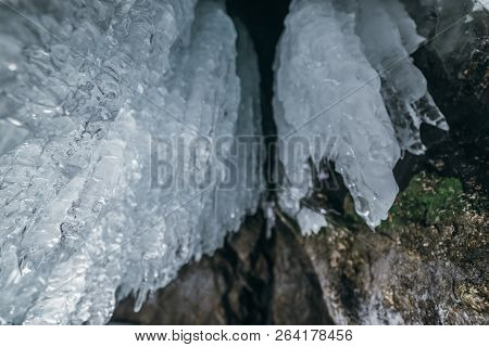 Winter Baikal. Olkhon Island. Ice Grotto. Thick Blue Ice And Icicles On The Coastal Rocks Of Olkhon 