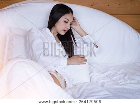 The Beautifu Laday Is Sitting On Bed,put Her Hand Touch Head,unhappy Feeling,headache From Tried And