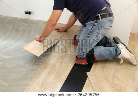 Work On Laying Flooring. Worker Installing New Vinyl Tile Floor.