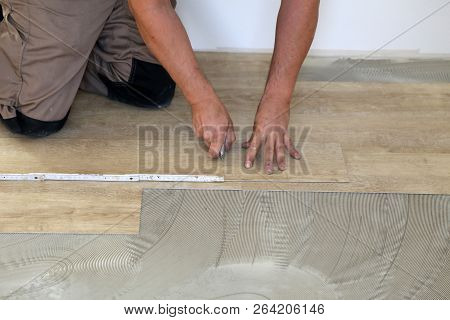 Work On Laying Flooring. Worker Installing New Vinyl Tile Floor.
