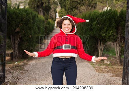 Christmas, Holidays, Humor And People Concept - Funny Happy Woman In Santa Suit Dancing Outdoors