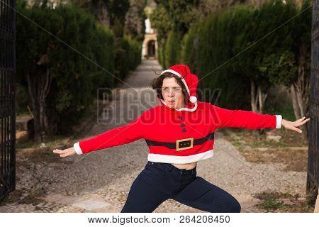 Christmas, Holidays, Humor And People Concept - Funny Happy Woman In Santa Suit Dancing Outdoors