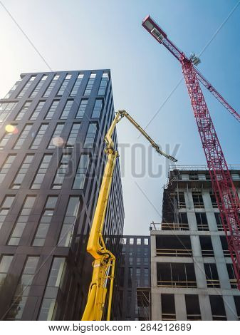 Highrise buildings under construction with comcrete pump and jib crane over clear blue sky
