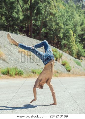 Young Man Break Dancing On The Road. Break Dancer Doing Extreme Sports Trick In A Urban Park Outdoor
