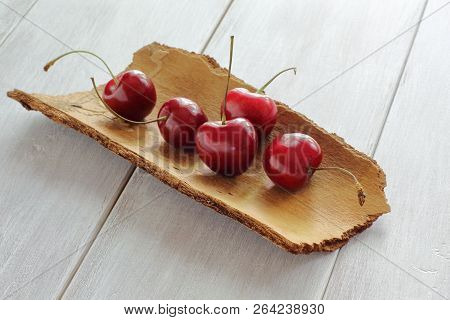 Juicy Red Cherry On The Pine Bark. Wooden Countertop.