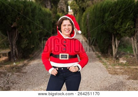Christmas, Holidays, Humor And People Concept - Funny Happy Woman In Santa Suit Dancing Outdoors