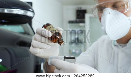 A Young Professional Master Holds A Jar In A White Coat, Safety Goggles, White Rubber Gloves.