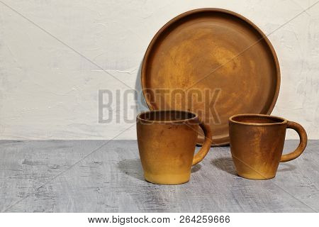 Round Clay Tray Near The White Concrete Wall And Clay Coffee Cups On A Dark Concrete Tabletop
