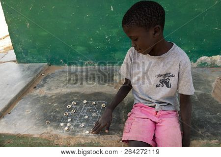 Orango Island, Guinea-bissau - February 3, 2018:  Portrait Of A Boy Playing A Game With Shells At Th