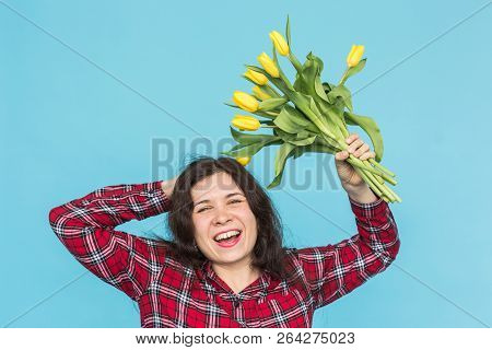 Laughing Young Caucasian Woman With Bouquet Of Tulips On Blue Background.