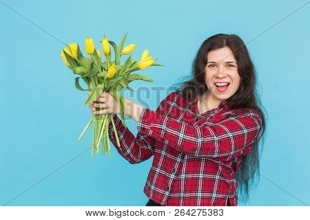 Laughing Young Caucasian Woman With Bouquet Of Tulips On Blue Background.