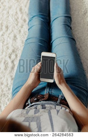Young Woman Holding Credit Card And Using Phone Sitting On Floor. Payment.  Online Shopping Concept.