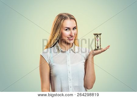 Young Smiling Blond Woman In White Shirt Holding Small Hourglass On Hand Looking At Camera