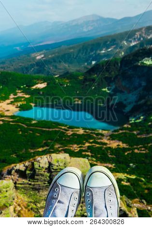 Alpine Mountain Lake, Green Meadows, Hiking Trail. Amazing Valley Landscape. Hiker Feet In Boots Han
