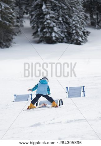 Cute Small Boy With Helemt And School Vest Learning Basic Skiing Skills