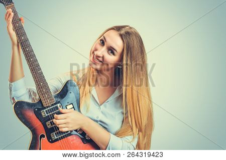 Coquette Young Blond Woman Playing Electric Guitar And Smiling At Camera On Gray Background