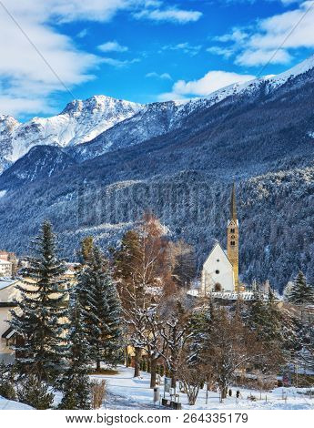 Winter landscape with small Church in front of the mountains, Scuol , Lower Engadine, Switzerland.