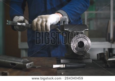 Man Worker Is Working With Iron Detail By Hammer On Vise Grip On Blacksmith Table.