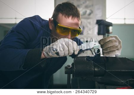 Man Worker Is Working With Iron Detail On Vise Grip On Blacksmith Table And Is Measuring A Diameter 