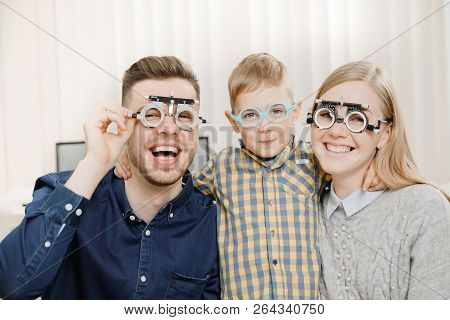 Cheerful Family With Small Child Reception Doctor Ophthalmologist Using Glasses, Eye Examination