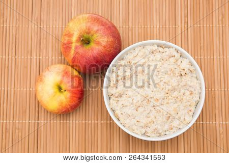 Oatmeal In White Bowl And Red Apple On White Background. Isolated On White. Healthy Food