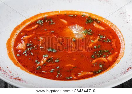 Soup With Meat, Olives, Herbs And Lemon In Plate, Served With Sour Cream, Peppers On Dark Wooden Bac