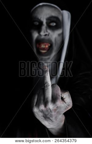 closeup of a frightening evil nun, with bloody teeth and scary eyes, wearing a typical black and white habit, giving the middle finger