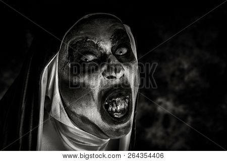 closeup of a scary evil nun, with frightening teeth, wearing a typical black and white habit, in black and white