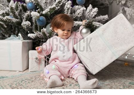 A Little Girl Is Playing With A Garland With A New Year Tree. Danger. Disobedient Child. Good New Ye