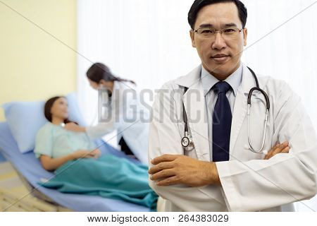 Portrait of Young adult Doctor with nurse and Patient in background.