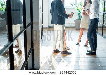 Partial View Of Business Colleagues Having Conversation In Hall During Coffee Break