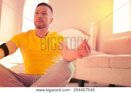 Thoughtful Relaxed Man Meditating On The Floor At Home
