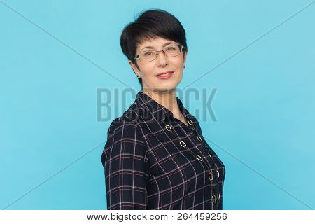 Middle Aged Woman With Pixie Haircut On Blue Background With Copy Space