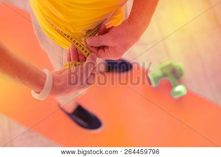 Attentive Serious Man Measuring His Waist In The Room
