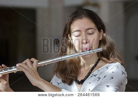 A Beautiful Woman Posing While Playing On A Flute