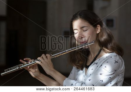 A Beautiful Woman Posing While Playing On A Flute