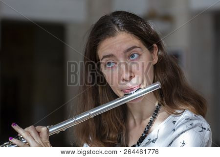 A Beautiful Woman Posing While Playing On A Flute