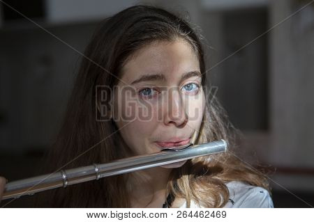 A Beautiful Woman Posing While Playing On A Flute