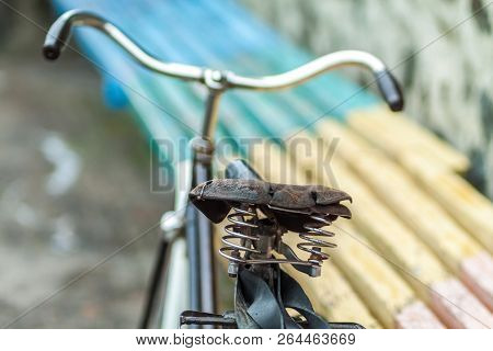 An Old Bicycle Seat With A Spring Shock Absorber. Vintage Bicycle On The Stone Wall Background.