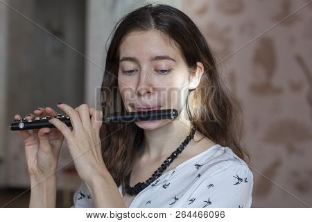 A Gorgeous Young Woman Sitting And Playing The Flute Piccolo