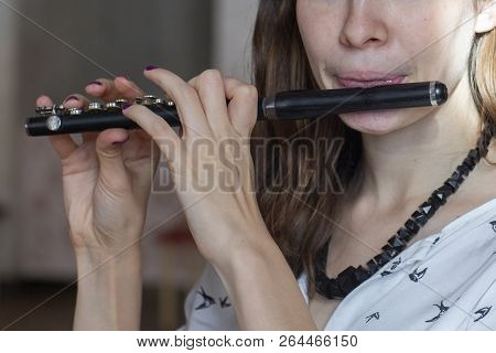 A Gorgeous Young Woman Sitting And Playing The Flute Piccolo