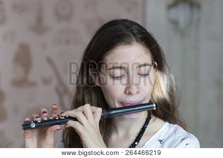 A Gorgeous Young Woman Sitting And Playing The Flute Piccolo