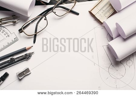 On The Wooden Table There Are Drawings, Compasses, Pencil, Elastic, Ruler, Sharpener And Glasses.