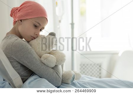 Weak Girl With Cancer Wearing Pink Headscarf And Hugging Teddy Bear