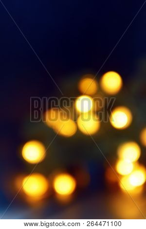 Background Of Blurry Yellow-orange Lights Of Christmas Tree Garland On Dark. Copy Space
