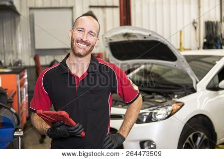 Handsome Mechanic Based On Car In Auto Repair Shop With Tablet On Hand