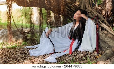 Beautiful Chinese Woman With A Traditional Suit With A Flute In Her Hands, Beautiful And Belligerent