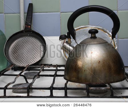 Estufa de gas sucio con hervidor de agua y la sartén en él.